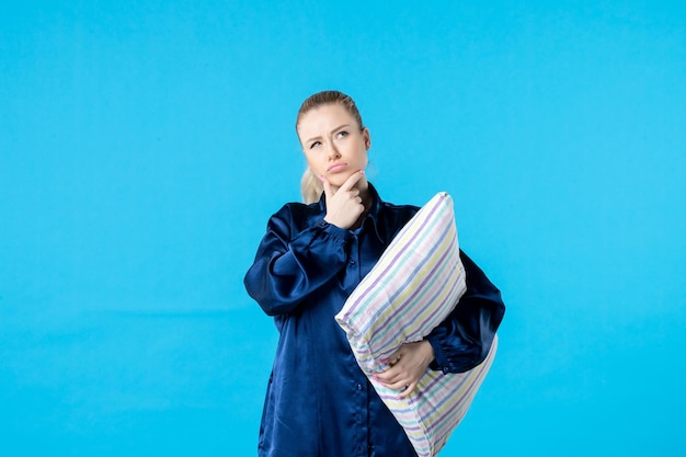 Photo front view young female in pajamas holding pillow on blue background woman color bed dream thought rest yawn sleep night