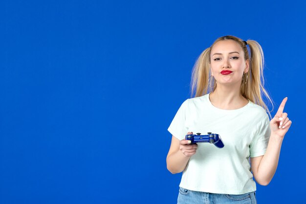 front view young female playing video game with gamepad on blue background online adult internet winning virtual joyful video player sofa