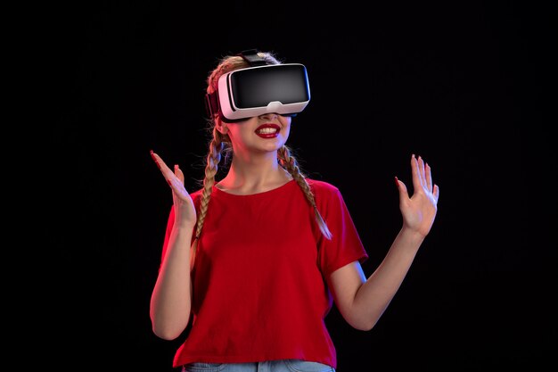 Front view of young female playing vr on dark wall