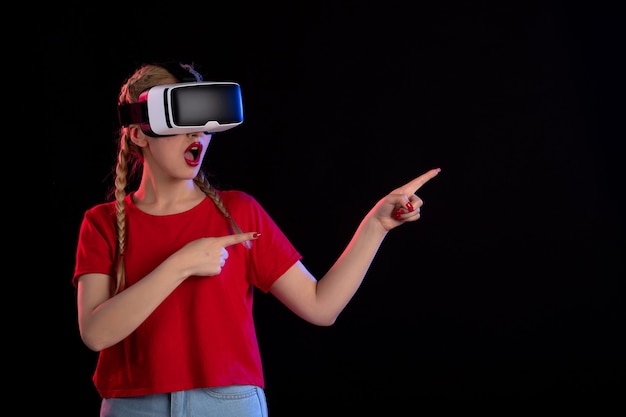 Front view of young female playing vr on dark wall