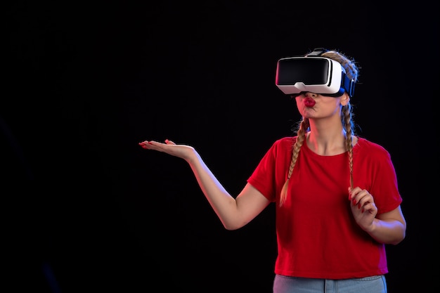 Front view of young female playing vr on dark wall