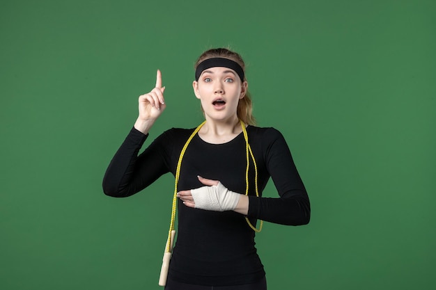 Front view young female with bandage around her hurt arm on green background sport athlete pain woman workout body colors injury health