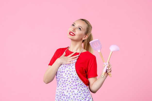 Front view young housewife with cutlery in her hands on pink wall