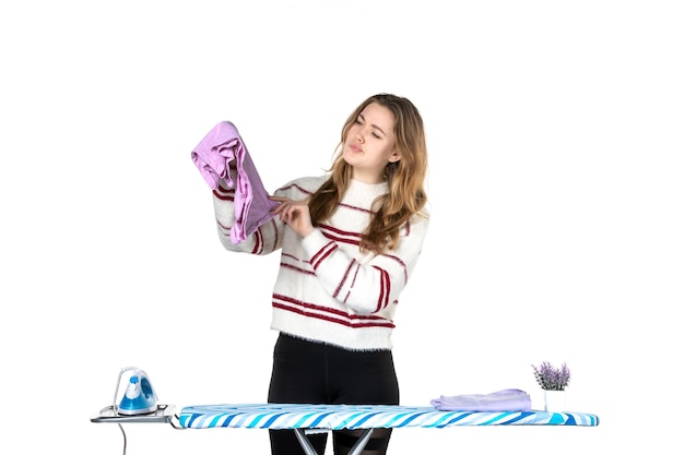 Front view young housewife with ironing board folding towels on white