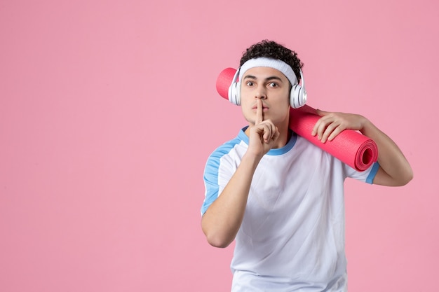 Front view young male athlete in sport clothes with yoga mat on pink wall