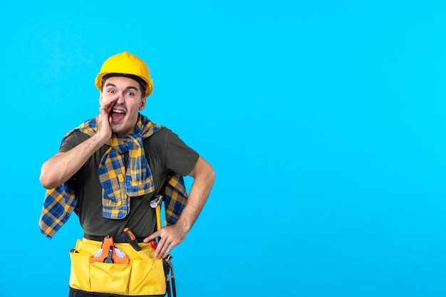 front view young male builder in yellow helmet on blue background worker tool constructor architecture flat building