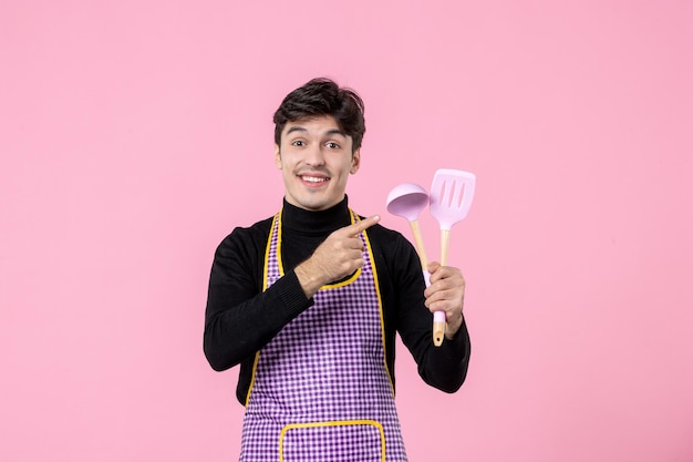 Front view young male in cape holding spoons on pink