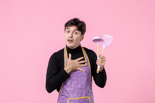 Front view young male in cape holding spoons on pink