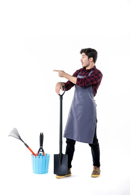 front view young male gardener with black shovel on a white background uniform soil work job flower garden digging ground