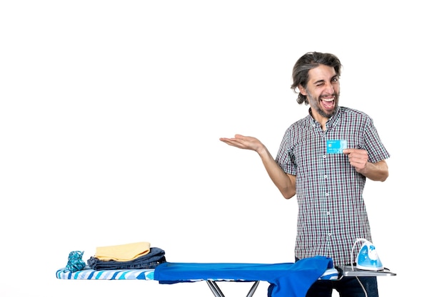 front view young male holding bank card behind ironing board on a white background man iron home laundry housework money clothes machine