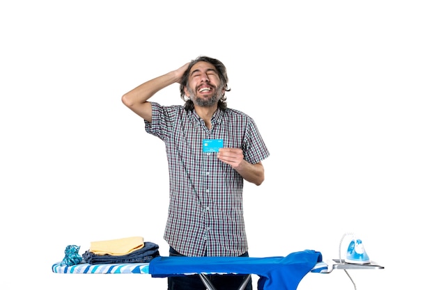 front view young male holding bank card behind ironing board on white background photo ironing machine man cleaning money housework