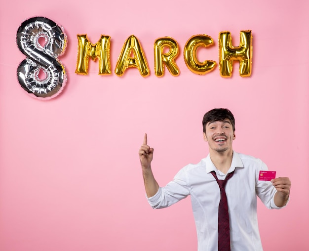 Front view young male holding bank card with march decoration on pink background money man presents equality shopping color holiday party feminine