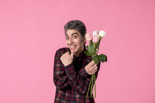 Front view young male holding beautiful pink roses on pink wall