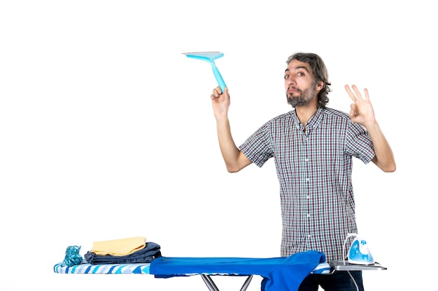 front view young male holding cleaner brush behind ironing board on white background home iron laundry clothes clean housework