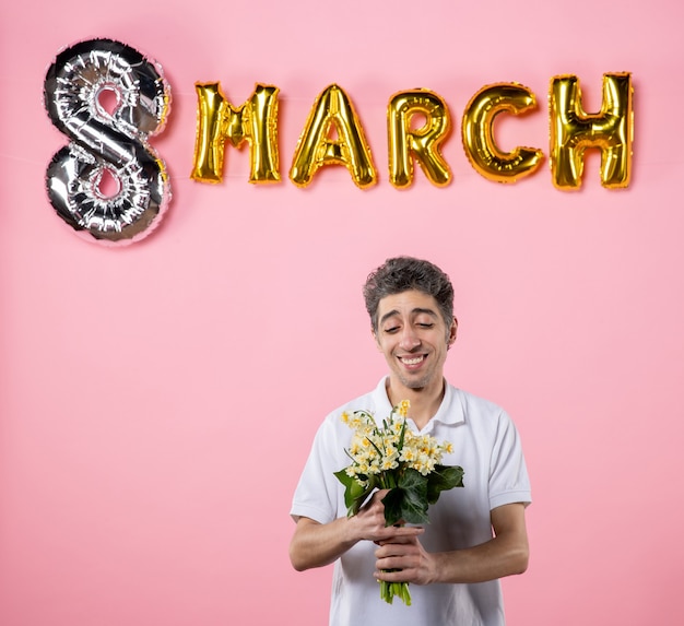 front view young male holding flowers for woman with march decorated pink background equality feminine sensual holiday womens day party emotion glamour color