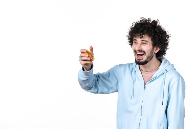 Front view young male holding fresh sliced orange on white