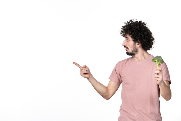 Front view young male holding little broccoli on white background salad diet horizontal vegetable weight health body