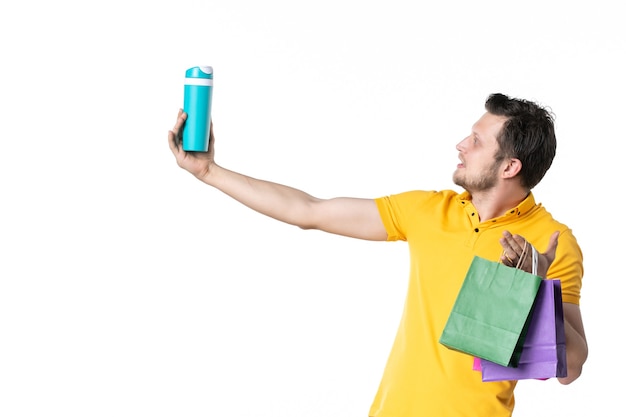 front view young male holding little packages and thermos on white background job color sport human uniform salesman worker water