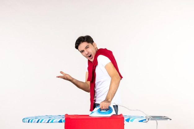 Front view young male ironing red towel on white surface