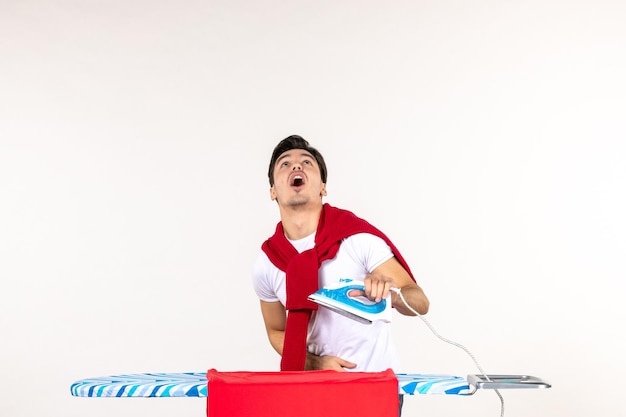 Front view young male ironing towel on white surface