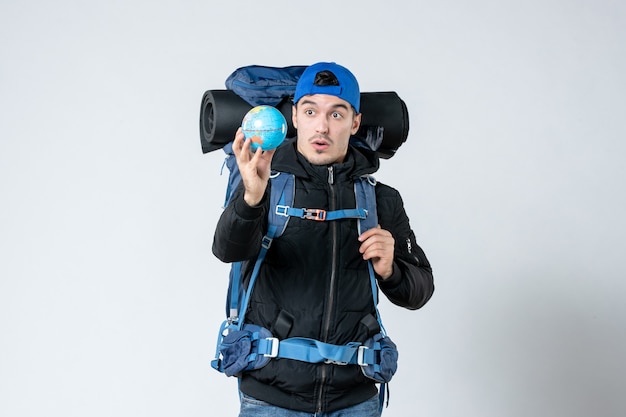 front view young male with backpack holding earth globe on white background campaign camp mountain sky nature forest air cold snow