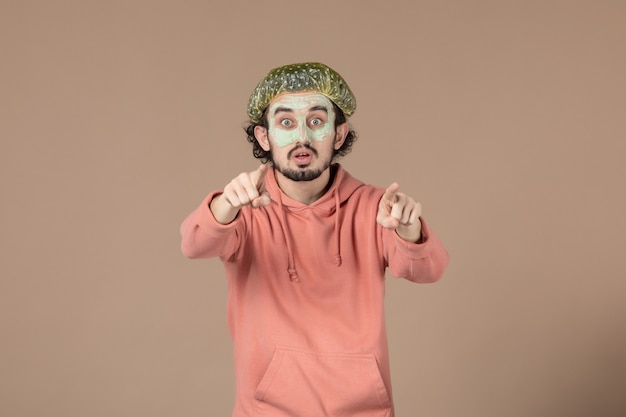 front view young male with bouffant cap and mask on his face on brown background spa hair skincare therapy skin salon facial