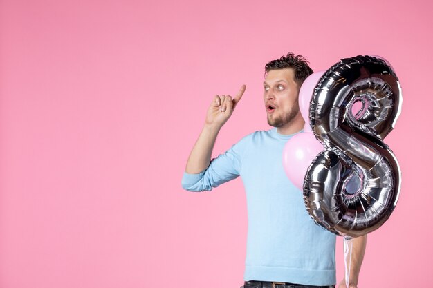 front view young male with cute balloons as march present on pink background love feminine womens day marriage equality date sensual fun