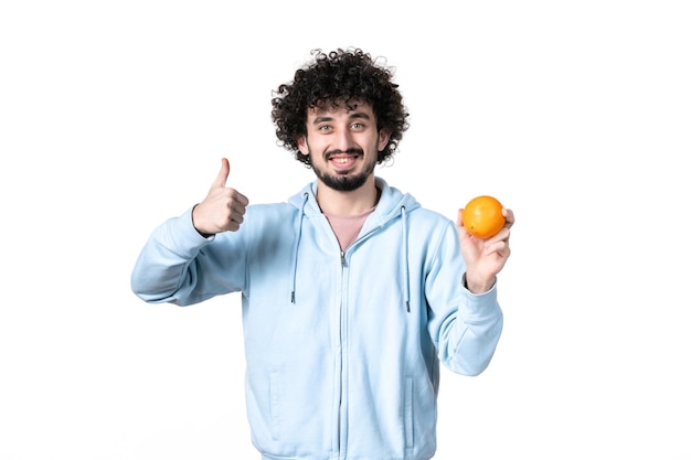 Front view young man holding fresh orange on white surface