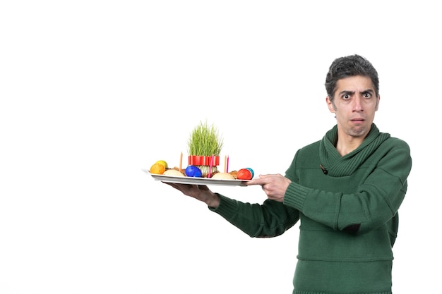 Photo front view of young man holding traditional novruz xoncha on white wall