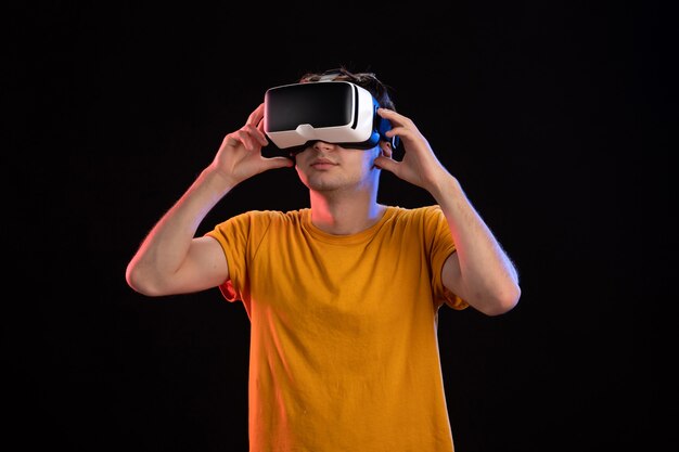 Front view of young man wearing vr headset on dark wall