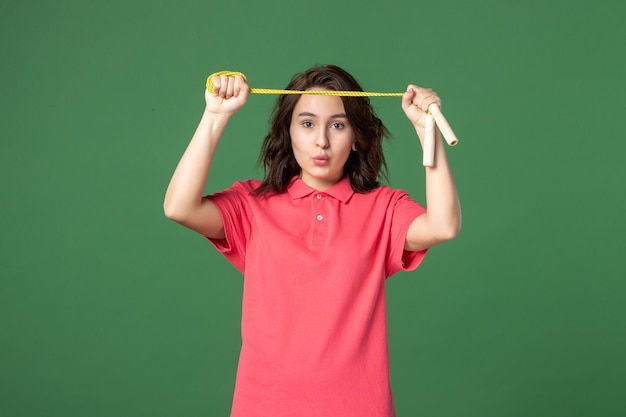 Front view young saleswoman holding skipping rope on green surface