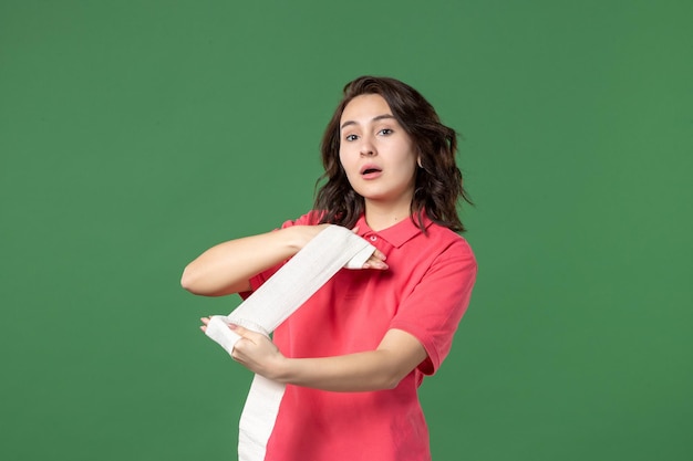 Front view young saleswoman tying her hands with bandage on green surface