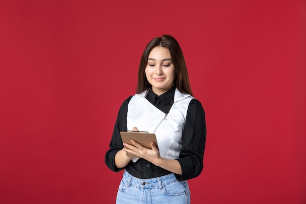 front view young waitress in uniform writing order on red background beauty woman dinner work evening job restaurant worker