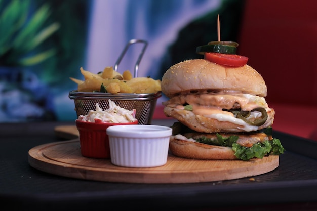 Front view yummy chicken cheese burger with french fries and sauces on wooden platter