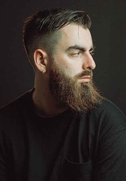 Frontal cinematic portrait of a handsome man with beard Looking serious and worried about the future Dark background movie cinema style portrait Mental health issues concept