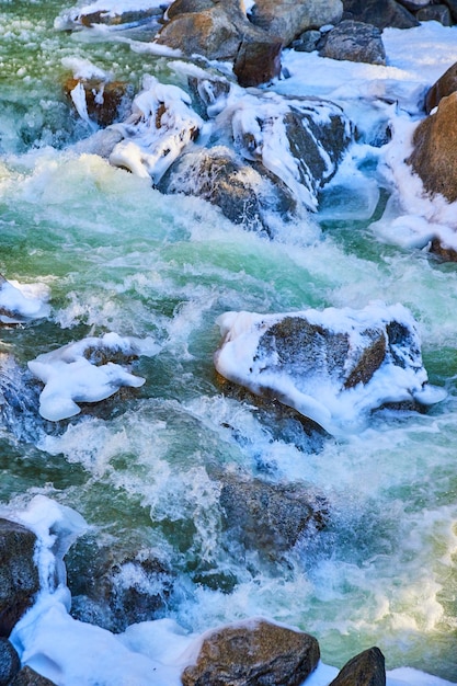 Frosted rocks and slushy snowy river cascading in early spring