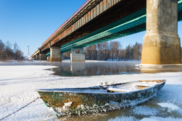 Frosty landscape boat on frozen river crossing