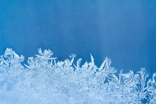 Photo frosty pattern on the blue window glass with copy space