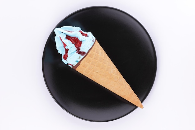 Frozen blue and red dessert Ice cream in a waffle cone on a black plate closeup Ice cream cone isolated on white background