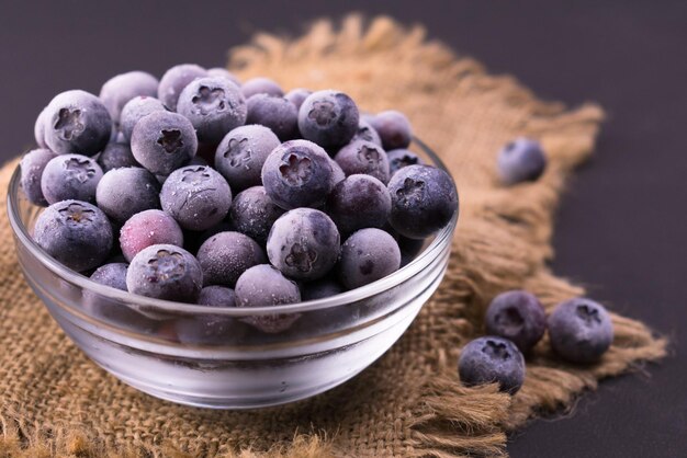 Frozen blueberries in a transparent glass bowl. Close-up.	 