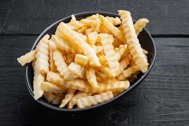 Frozen crinkle oven fries set, on black wooden table background