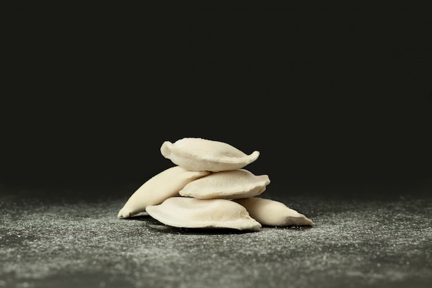 Frozen dumplings on a dark surface sprinkled with flour