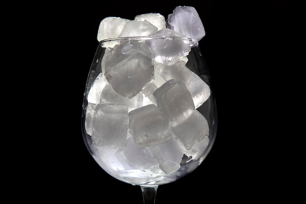 frozen ice cubes in an empty wine glass on a dark background