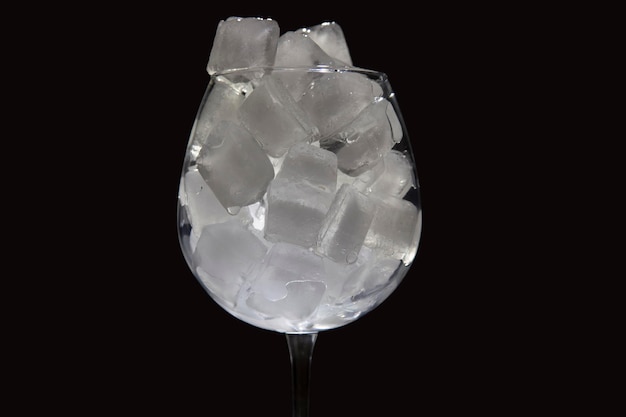 frozen ice cubes in an empty wine glass on a dark background