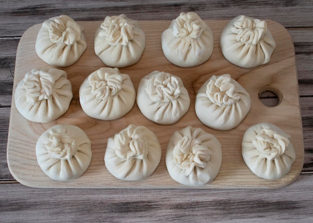 Frozen khinkali with lamb meat on a wooden board and background