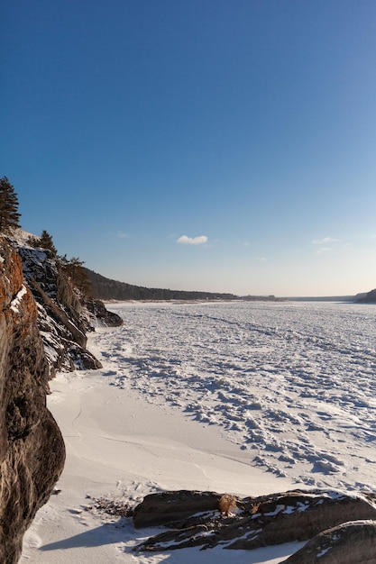 A frozen lake or river in winter. Near the forest and mountains in the snow. winter landscapes