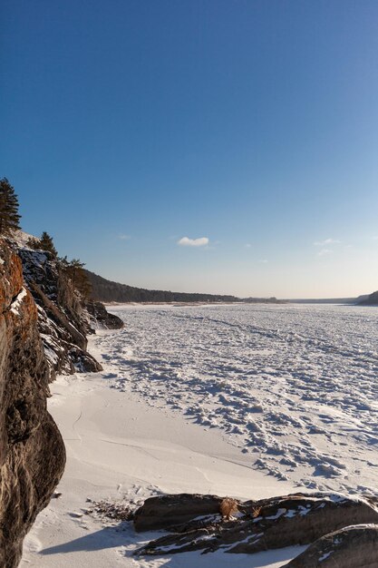 A frozen lake or river in winter Near the forest and mountains