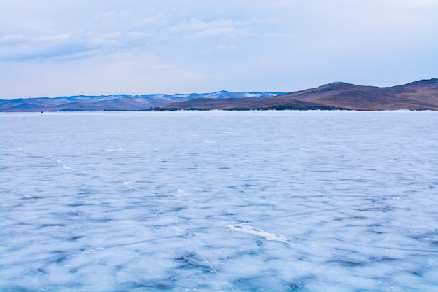 Frozen lake with rock islands at background, Baikal Lake in Russia, landscape photography, travel in Siberia, Russia