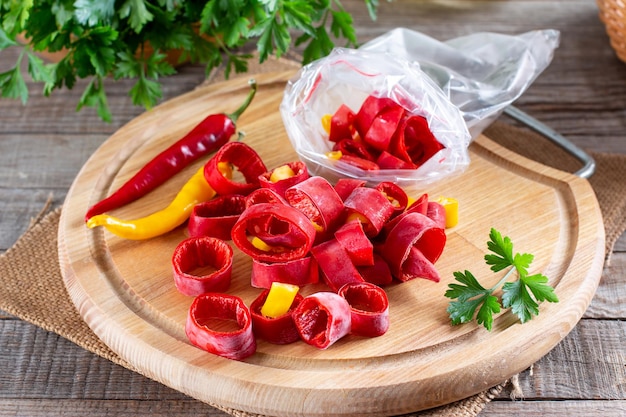 Frozen red peppers. Frozen hot pepper on a wooden board on the table. Frozen food. Frozen vegetables.