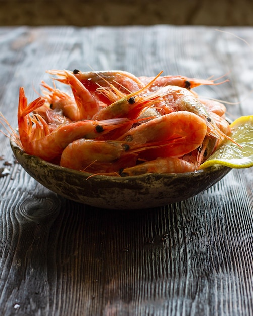 Frozen shrimp with lemon on a dark wooden background